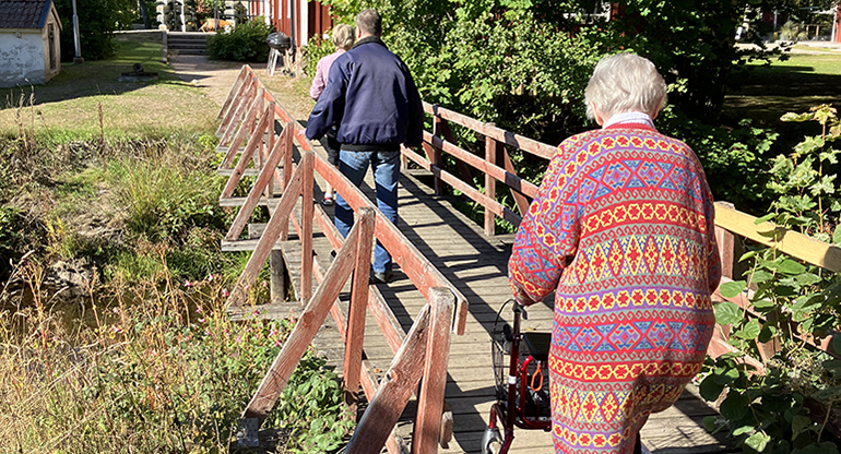 Flera äldre personer på en gångbro. Foto.