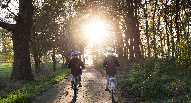 Två barn som cyklar på en grusväg. Foto.
