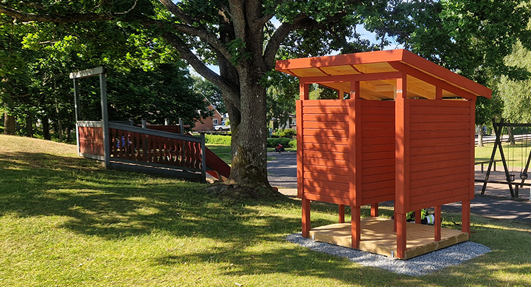 Röd nybyggd badhytt på gräsplan vid badplatsen Sjöparken i Lenhovda