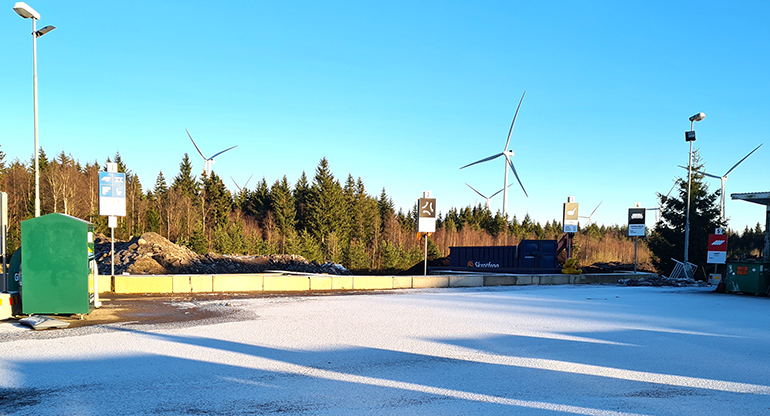 Linneberga återvinningscentral med vindkraftverk i bakgrunden. Foto.
