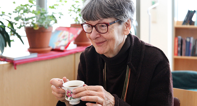 Äldre kvinna dricker kaffe. Foto.